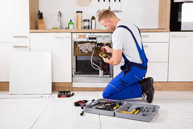 Technician diagnosing the electrical components of a built-in kitchen appliance