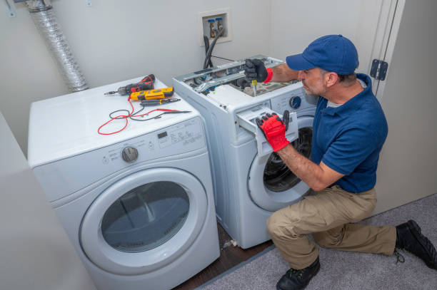 Technician repairing a washer beside a residential dryer