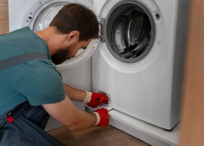 Technician servicing the lower access area of a washing machine